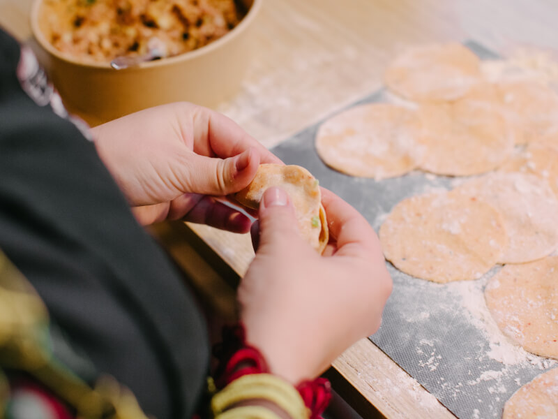 Two hands folding a gyoza wrapper